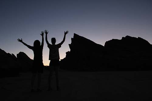 vasquez rocks two people standing on field under gray sky during daytime united states